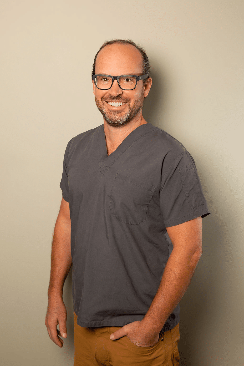 Dr. Garry Wessels wearing a gray outfit, smiling and standing in a professional setting.