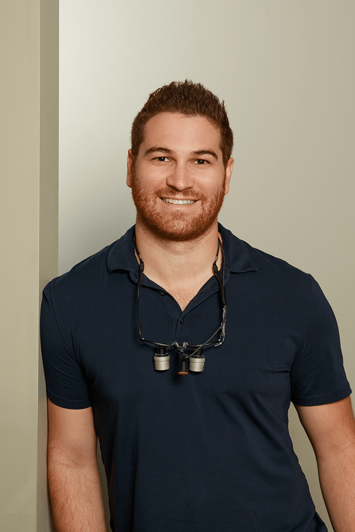 Dr. Torresan wearing a blue polo shirt, standing confidently with a neutral expression.