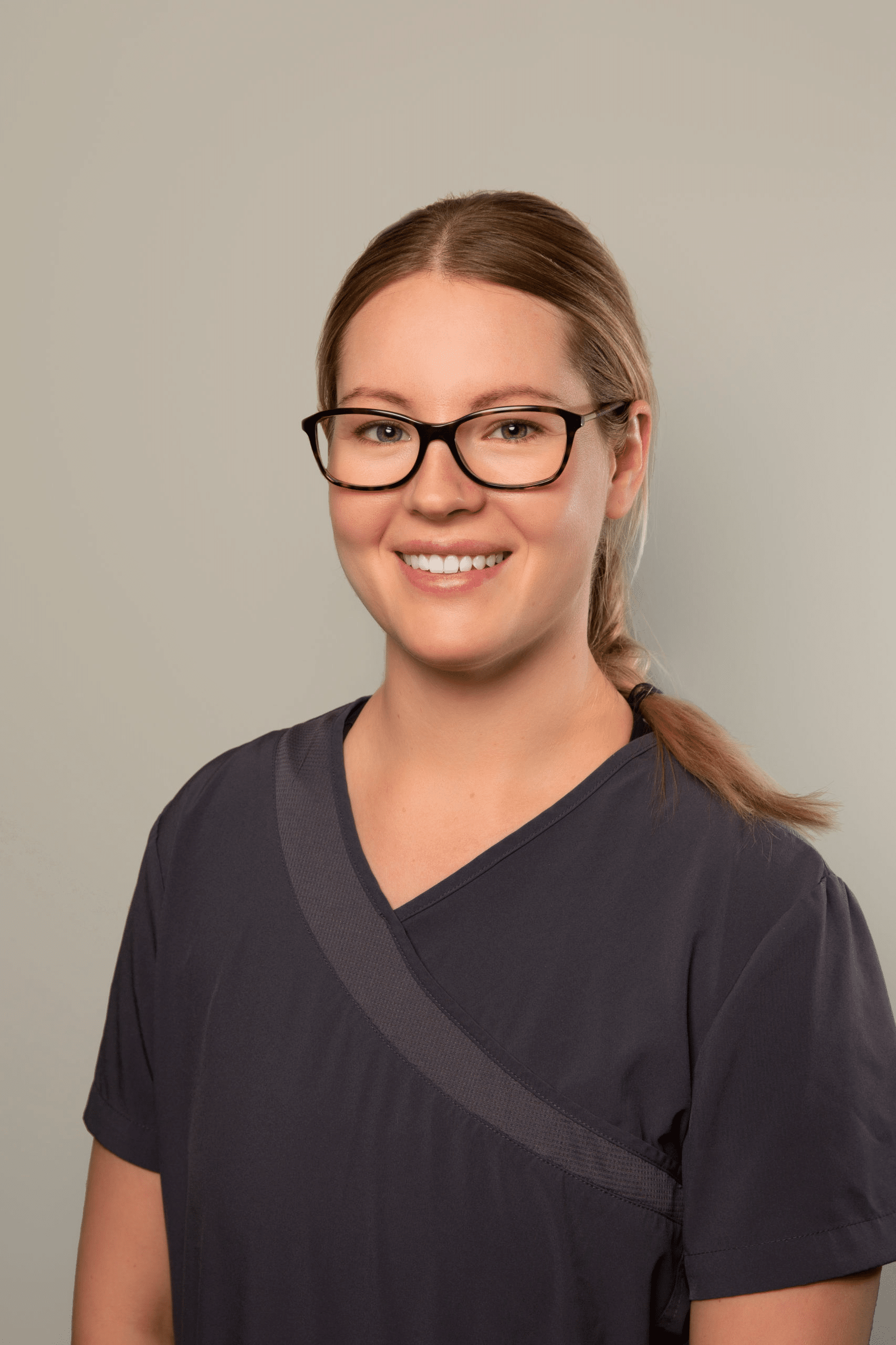 A woman named Megan, wearing glasses and a sweater, poses as a staff member of Dr. Gary Wessels Inc.